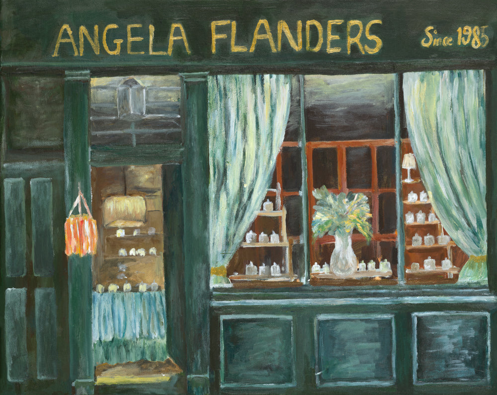 An oil painting of a storefront with the text 'ANGELA FLANDERS Since 1985' at the top. The shop facade is painted in deep forest green with gold lettering, light green curtains, and a window display filled with small white bottles and a vase of flowers.